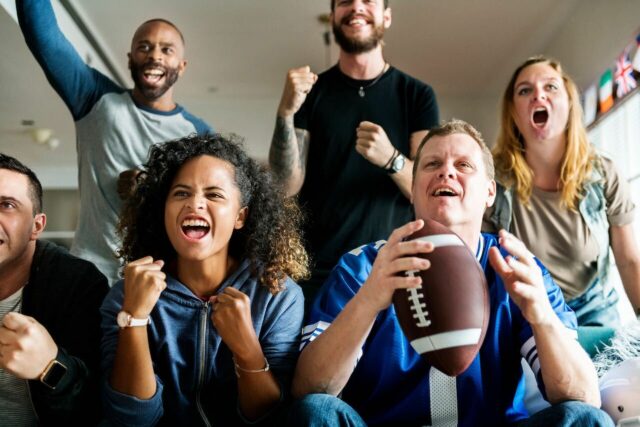 Friends cheering sport league together picture of a group of friends cheering for a game with one man holding a football