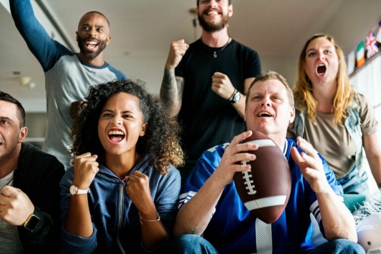 picture of a group of friends cheering for a game with one man holding a football